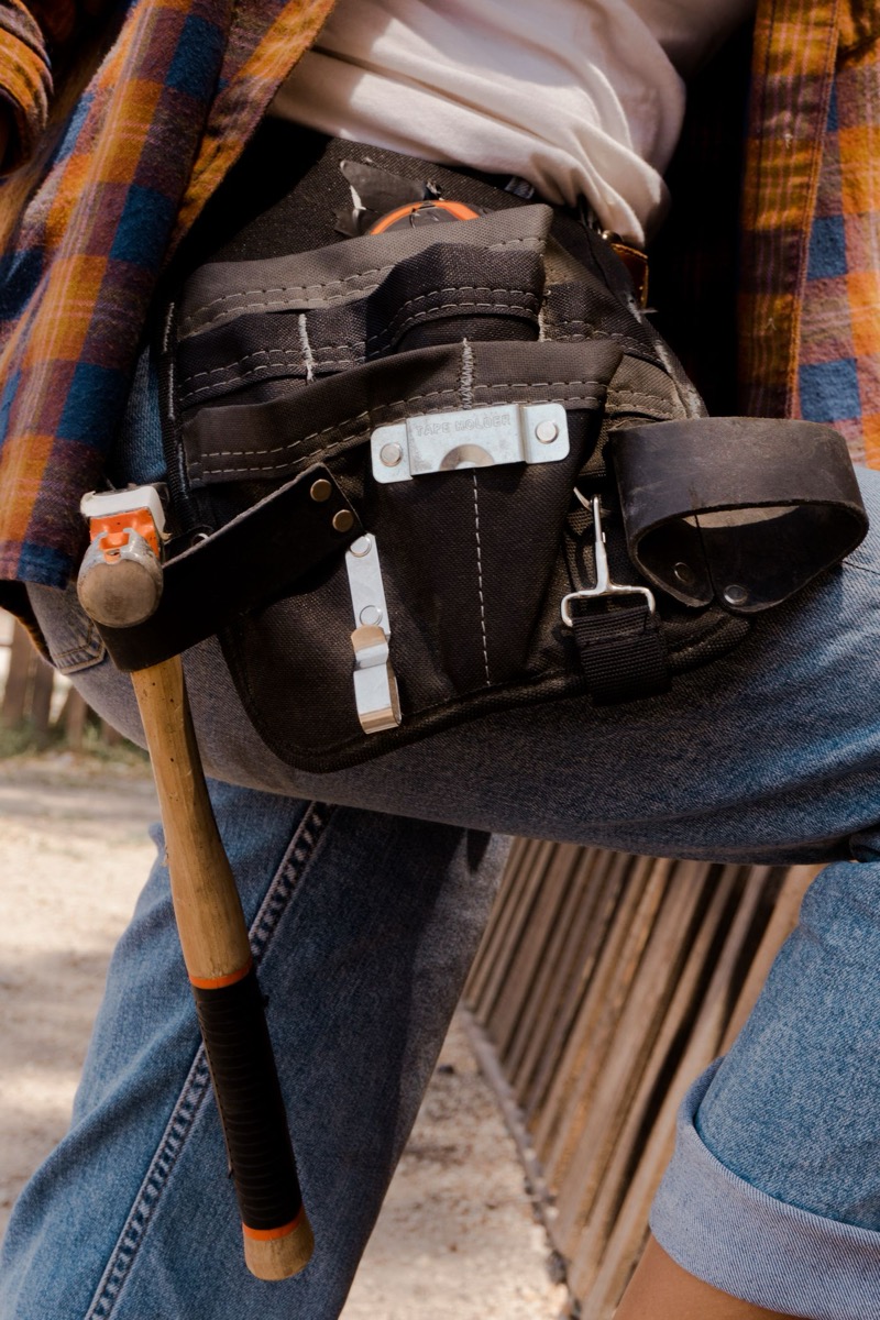 A well-used carpenter's tool belt with hammer and tape measure