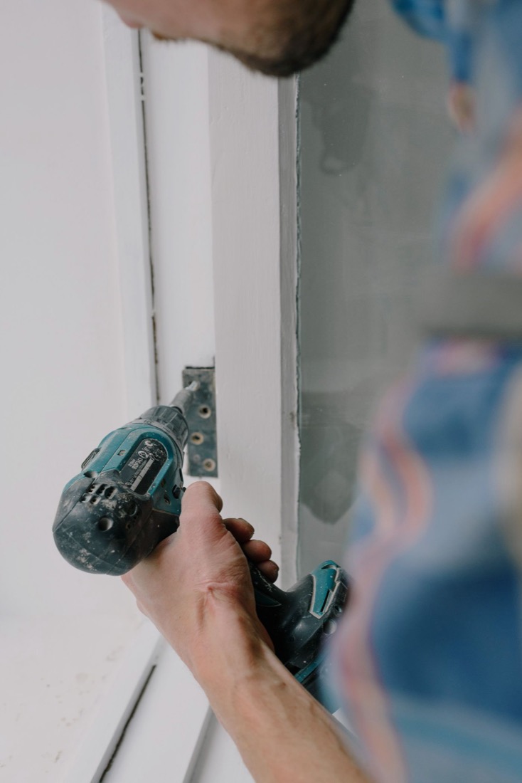 Driving a screw into a door hinge with a cordless drill